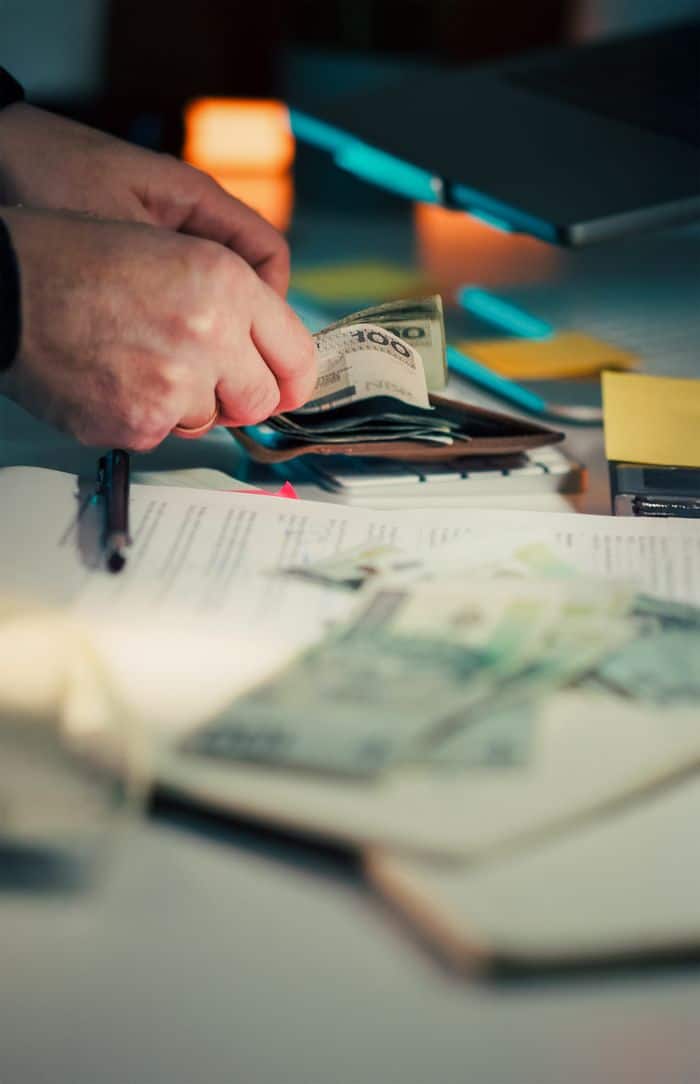 Crafting Captivating Headlines: Your awesome post title goes here Close-up of hands counting cash next to a wallet and documents on a desk.